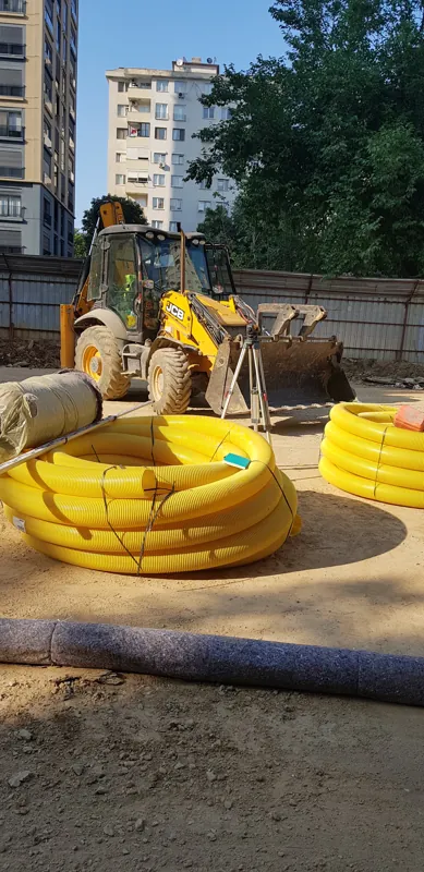 Binalar arasındaki çalışma alanında kazıcı yükleyici ve sarı borular